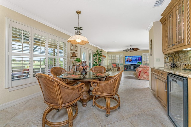 tiled dining space featuring beverage cooler, a healthy amount of sunlight, and crown molding