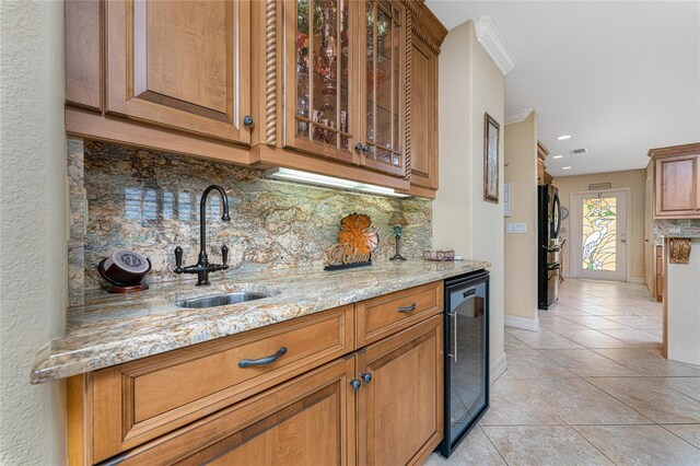 kitchen featuring light stone counters, light tile patterned floors, sink, decorative backsplash, and beverage cooler