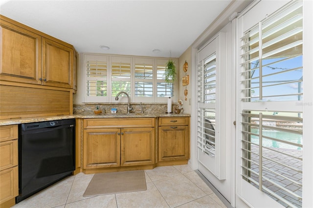 kitchen featuring light stone countertops, sink, black dishwasher, and light tile patterned floors