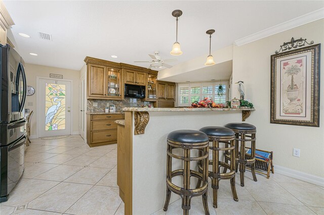 kitchen with a kitchen bar, kitchen peninsula, tasteful backsplash, ceiling fan, and stainless steel refrigerator