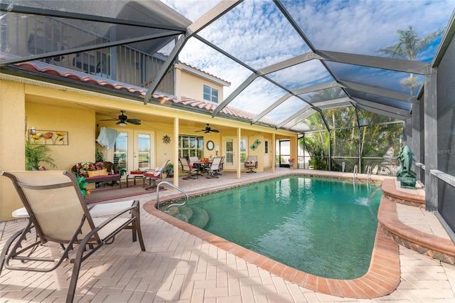 view of pool featuring glass enclosure, an outdoor hangout area, a patio area, pool water feature, and ceiling fan