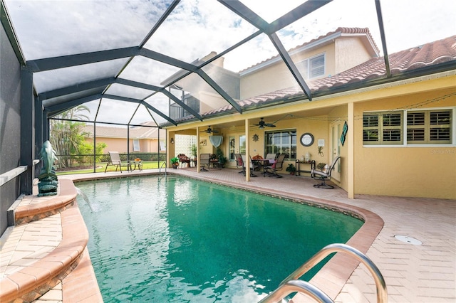 view of pool featuring glass enclosure, ceiling fan, and a patio