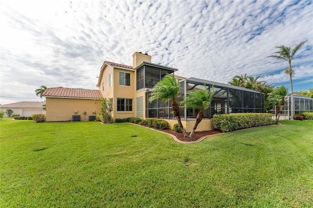 rear view of house with a lanai, central AC unit, and a yard