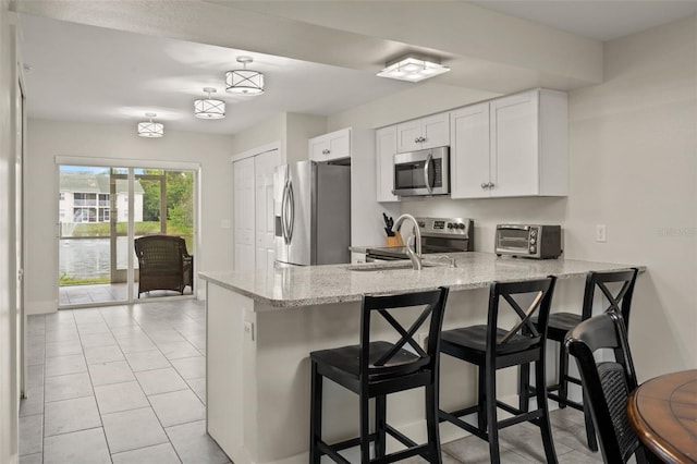 kitchen with white cabinetry, a kitchen bar, stainless steel appliances, and kitchen peninsula