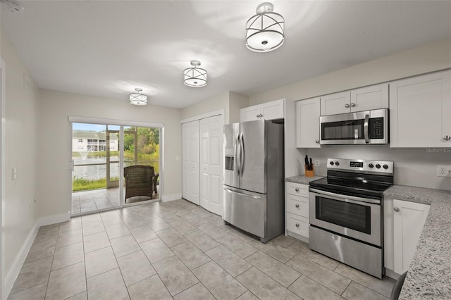 kitchen featuring stainless steel appliances, white cabinets, light tile patterned floors, and light stone counters