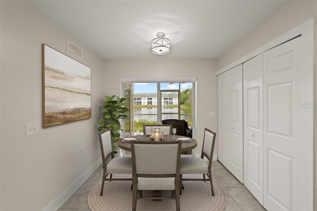 dining area featuring a water view and light tile patterned floors