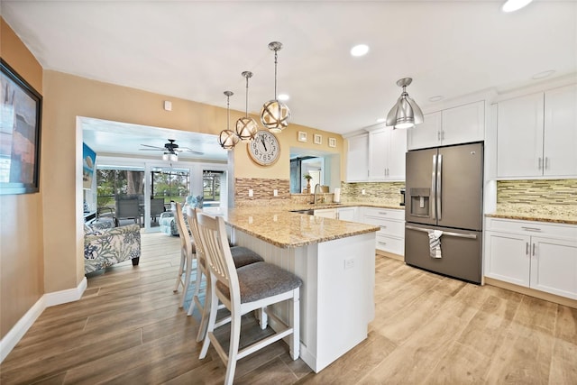 kitchen with stainless steel refrigerator with ice dispenser, a breakfast bar area, pendant lighting, and kitchen peninsula