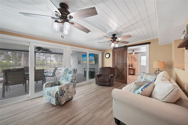 living room with a barn door, ceiling fan, wood ceiling, and light wood-type flooring