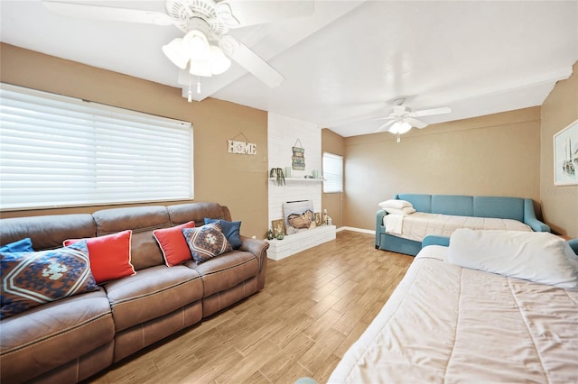 bedroom featuring a brick fireplace, ceiling fan, and wood-type flooring