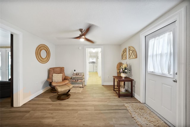 foyer featuring washing machine and clothes dryer, light hardwood / wood-style floors, and ceiling fan