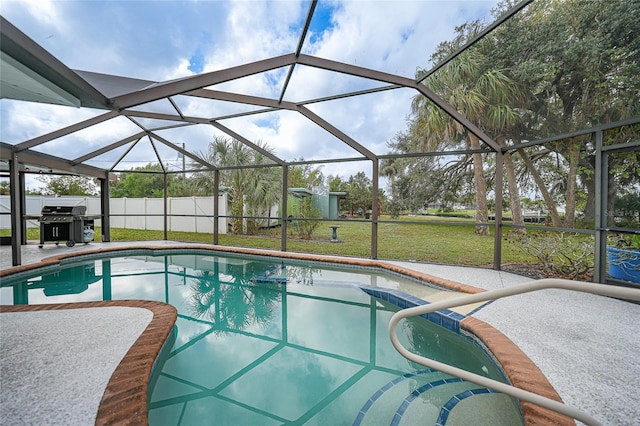 view of swimming pool featuring a storage unit, a lawn, glass enclosure, and a patio area