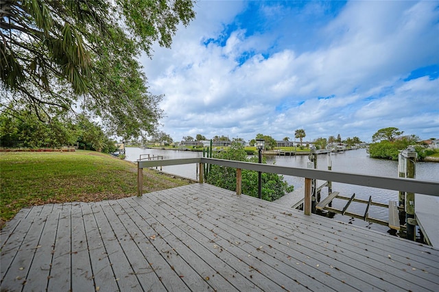 wooden deck featuring a dock, a yard, and a water view