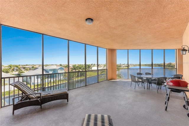 sunroom featuring a water view