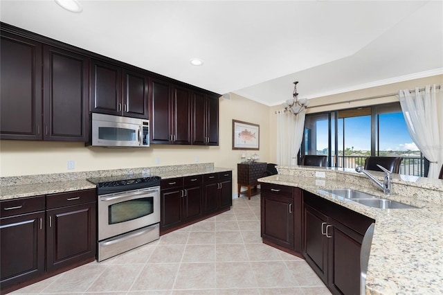 kitchen with sink, light stone counters, a notable chandelier, dark brown cabinets, and appliances with stainless steel finishes