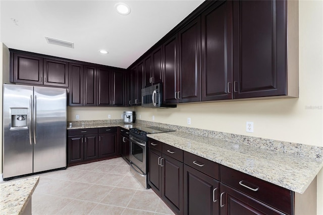 kitchen with light stone countertops, dark brown cabinetry, stainless steel appliances, and light tile patterned flooring