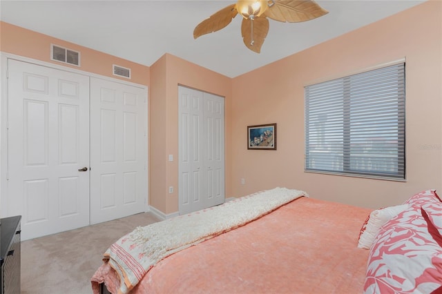 carpeted bedroom with ceiling fan and two closets