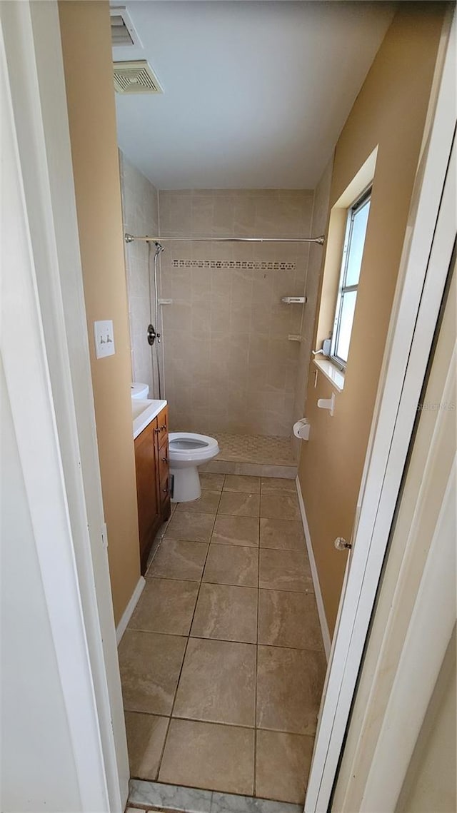 bathroom featuring tile patterned flooring, vanity, toilet, and a tile shower