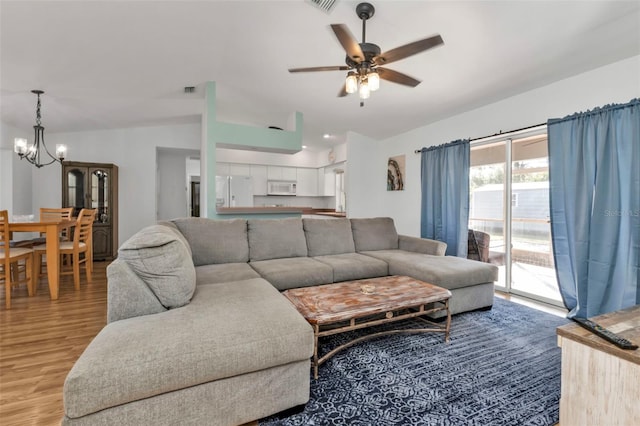 living room featuring ceiling fan with notable chandelier, light wood-type flooring, and lofted ceiling