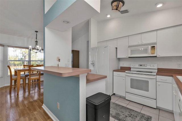 kitchen featuring an inviting chandelier, light hardwood / wood-style floors, lofted ceiling, white appliances, and white cabinets