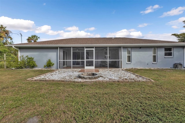 rear view of property featuring a sunroom, an outdoor fire pit, and a lawn