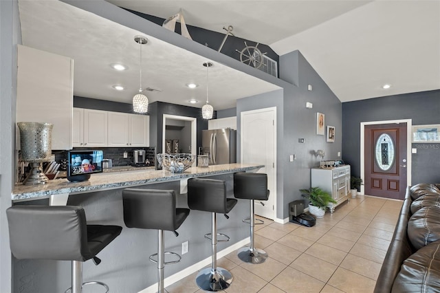 kitchen with vaulted ceiling, white cabinets, stainless steel refrigerator with ice dispenser, kitchen peninsula, and pendant lighting