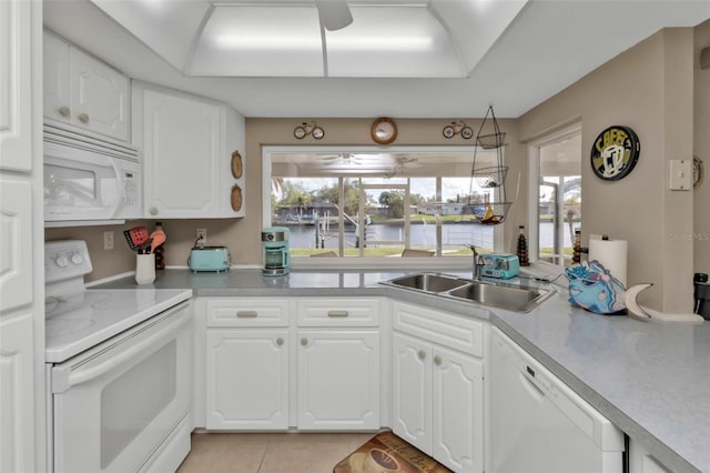 kitchen featuring sink, white cabinets, light tile patterned flooring, white appliances, and a water view