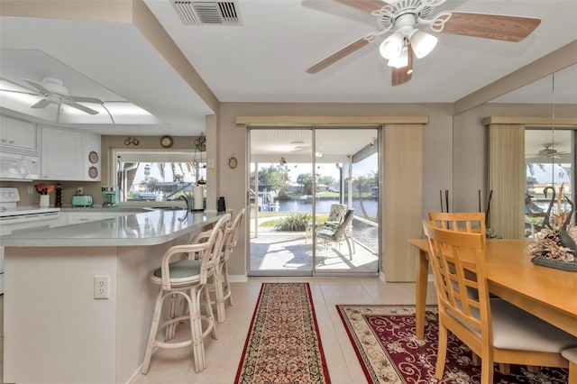 kitchen with kitchen peninsula, a water view, a healthy amount of sunlight, and white appliances