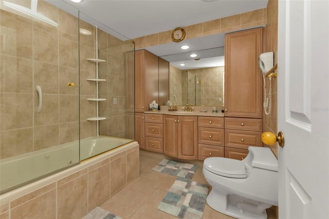 full bathroom with vanity, shower / bath combination with glass door, tile walls, tile patterned flooring, and toilet