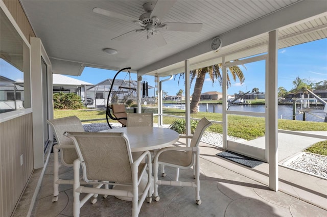 sunroom / solarium featuring ceiling fan and a water view