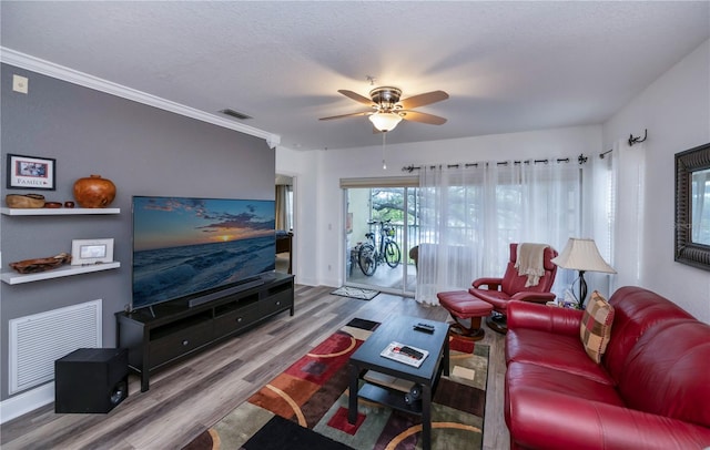 living room featuring hardwood / wood-style flooring, ceiling fan, a textured ceiling, and crown molding