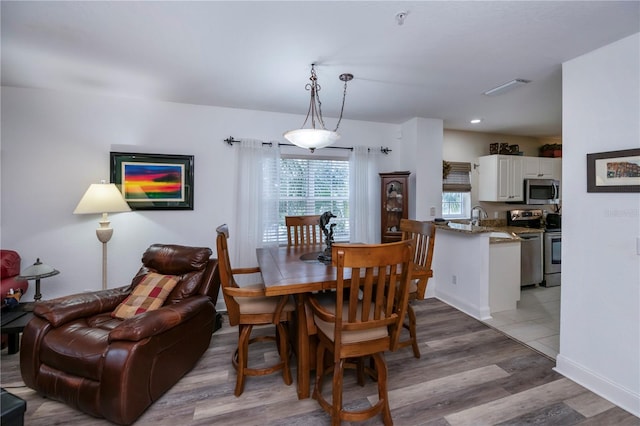 dining space with light hardwood / wood-style flooring and sink