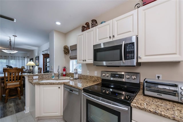 kitchen featuring stainless steel appliances, white cabinetry, sink, kitchen peninsula, and light hardwood / wood-style flooring