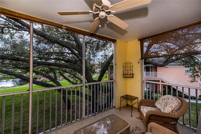 sunroom / solarium featuring a water view and ceiling fan