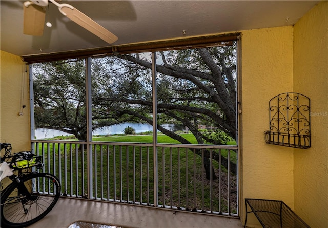 sunroom / solarium with a water view and ceiling fan