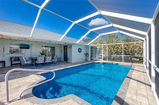 view of pool with glass enclosure, a patio, and ceiling fan