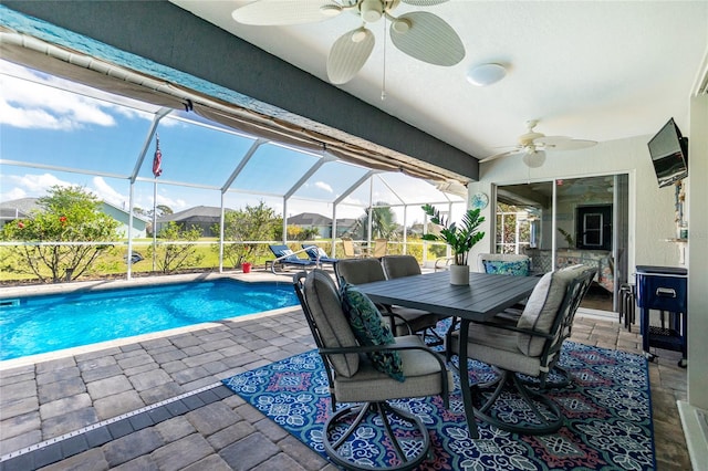 view of pool with glass enclosure, a patio, and ceiling fan