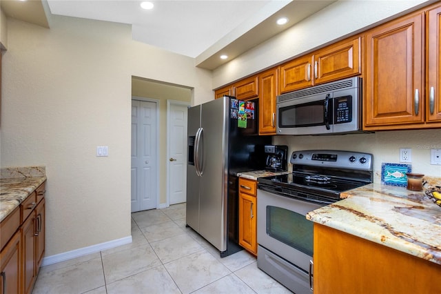 kitchen with light stone countertops, appliances with stainless steel finishes, and light tile patterned flooring