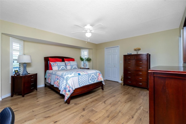 bedroom featuring ceiling fan, a textured ceiling, a closet, and light hardwood / wood-style flooring