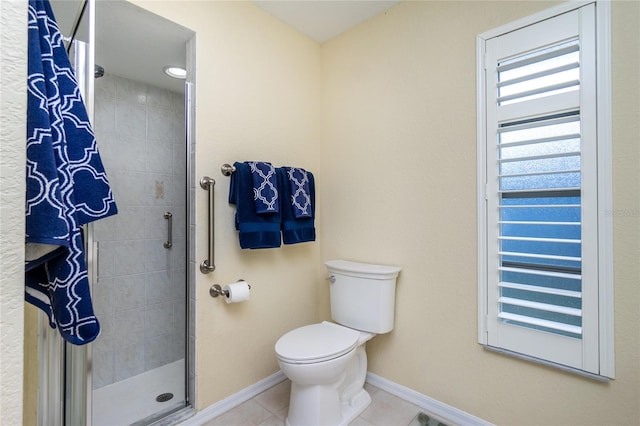 bathroom with tile patterned flooring, toilet, and a tile shower