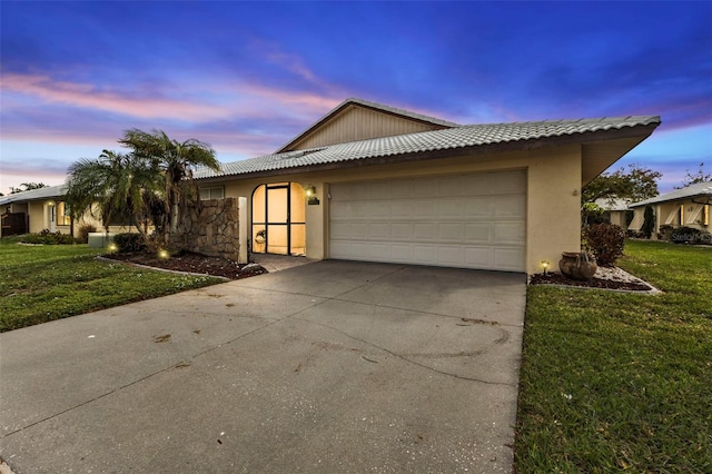 view of front of home with a garage and a lawn