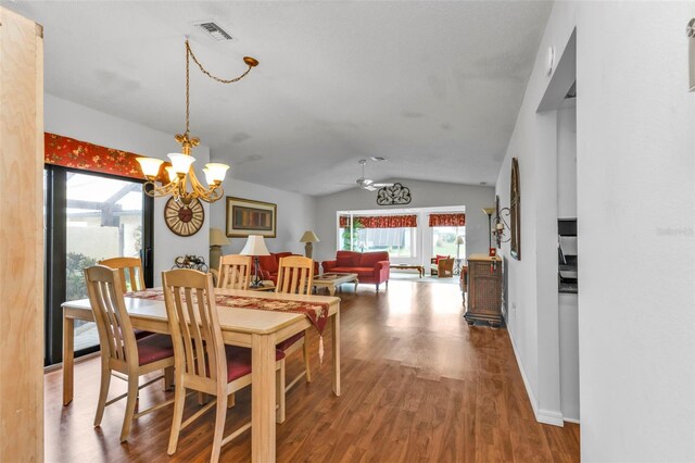 dining room with wood-type flooring, ceiling fan with notable chandelier, and lofted ceiling