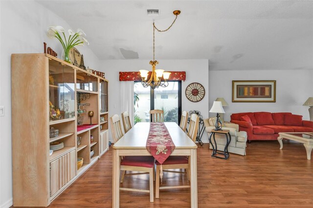 dining area featuring wood-type flooring, lofted ceiling, and a notable chandelier