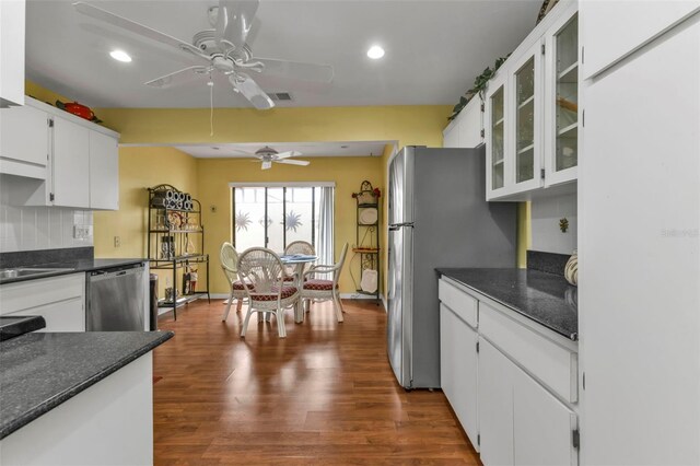 kitchen with white cabinetry, appliances with stainless steel finishes, dark hardwood / wood-style floors, and dark stone countertops