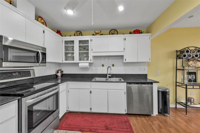 kitchen with light hardwood / wood-style flooring, appliances with stainless steel finishes, sink, and white cabinets