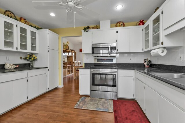 kitchen with stainless steel appliances, hardwood / wood-style flooring, white cabinetry, and decorative backsplash