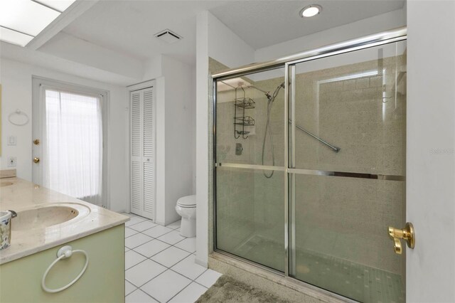 bathroom with toilet, vanity, tile patterned flooring, and a shower with shower door