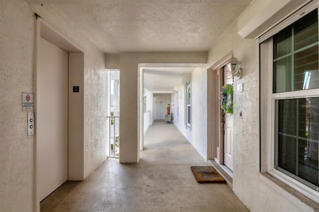 hallway featuring elevator and a textured ceiling