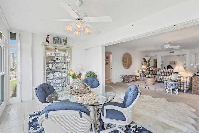 dining area featuring ceiling fan, light tile patterned flooring, and a textured ceiling