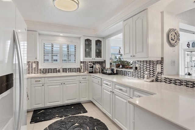 kitchen with tasteful backsplash, a wealth of natural light, white cabinets, and white appliances