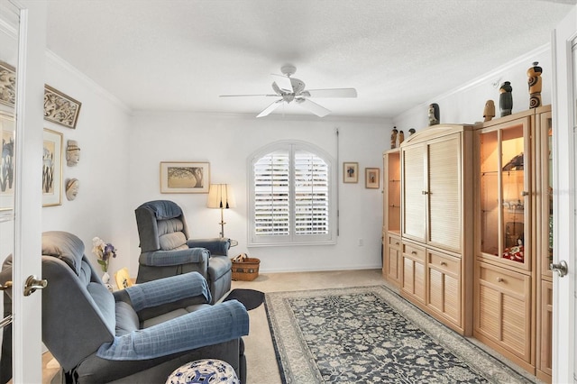 sitting room with a textured ceiling, ceiling fan, crown molding, and carpet